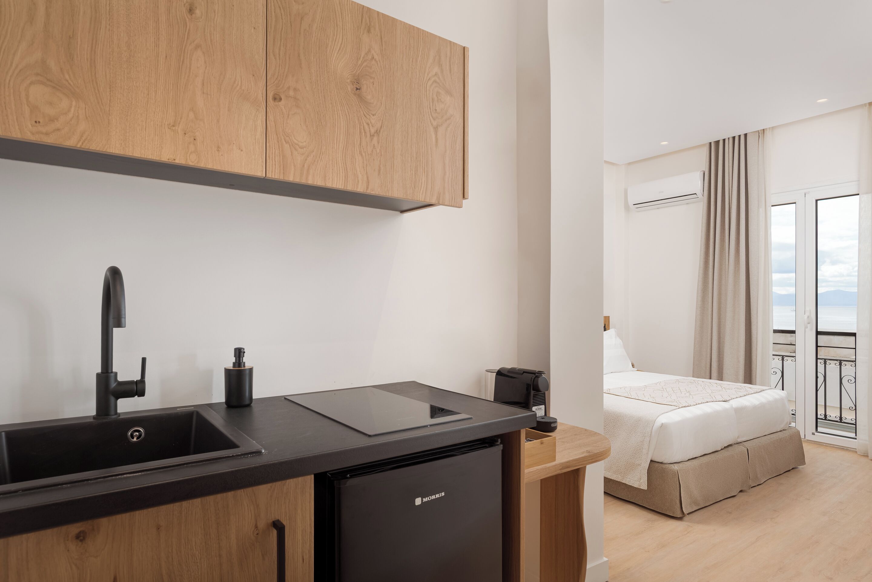 A modern kitchen with a sink, a black refrigerator, and wooden cabinets.