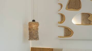 Une chambre moderne avec une tête de lit en bois, un luminaire suspendu et une étagère murale agrémentée d’éléments décoratifs.
