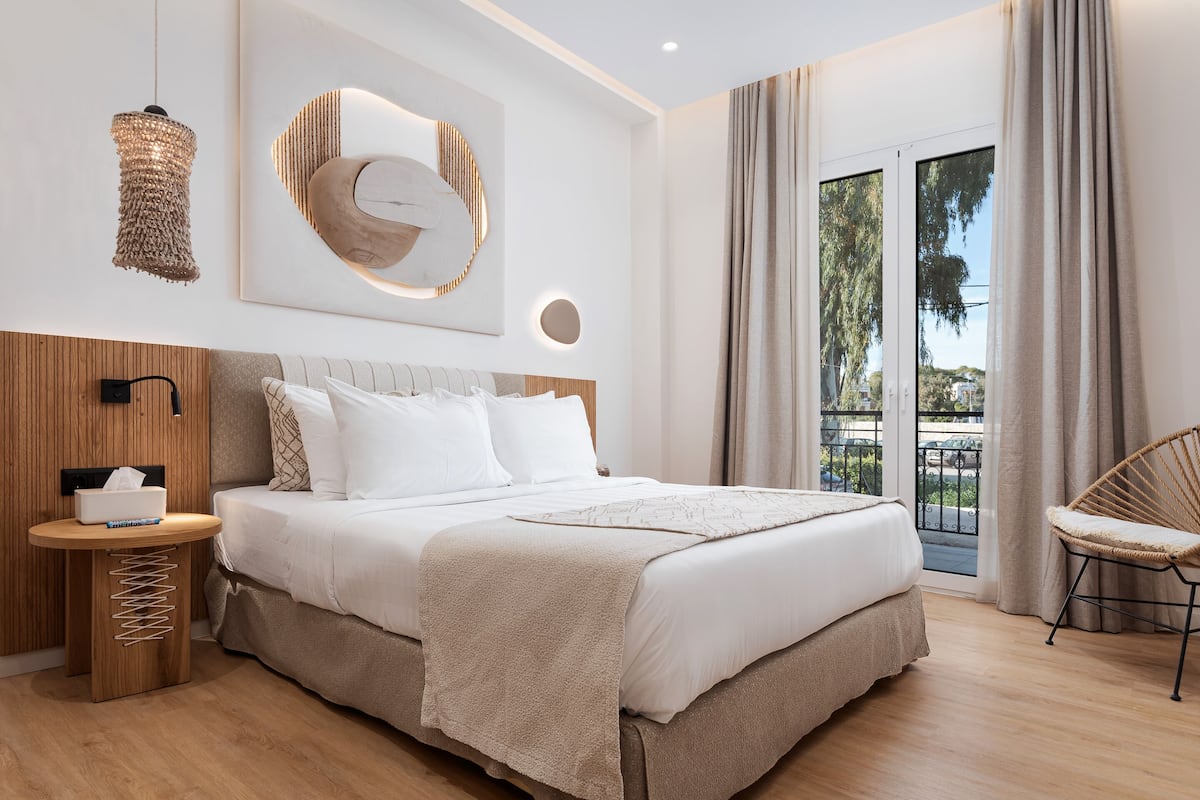 Une chambre à coucher moderne avec un grand lit, une table de chevet avec un boîte de mouchoirs, un luminaire fixé au mur et une vue sur l’extérieur grâce à une porte coulissante.
