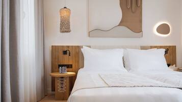 Habitación de hotel ordenada con cama, mesita de noche, lámpara y arte abstracto en la pared.