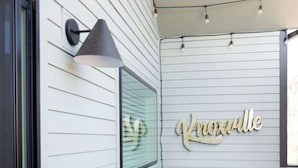 A deck with Adirondack chairs and a neon sign reading "Knoxville."