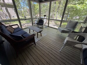 A covered outdoor deck with wicker furniture, a table, and a lamp.