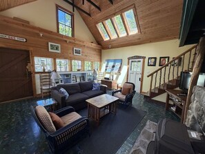 A cozy interior with a wooden ceiling, a sofa, a dining table, and a staircase.