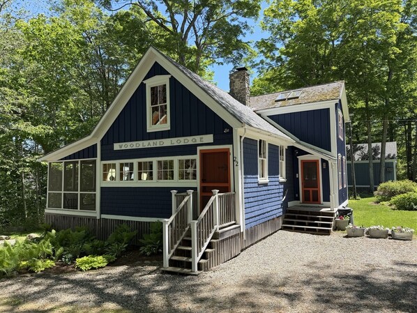 A two-story lodge with a steep gable roof, a front porch, and a gravel driveway.