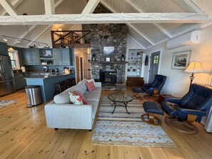 A spacious living area with a stone fireplace, a sofa, a coffee table, and a leather chair.