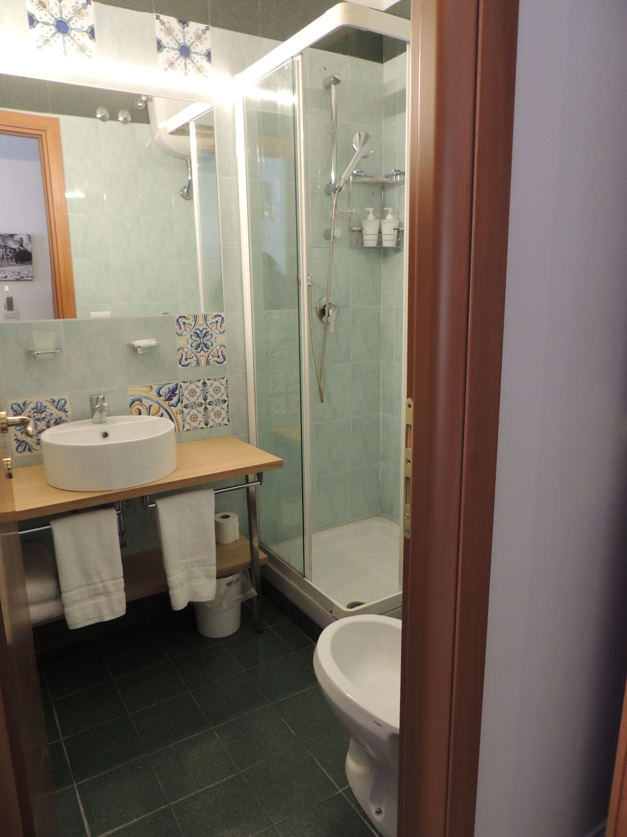 A bathroom with a glass-enclosed shower, a sink with a mirror, and a toilet.