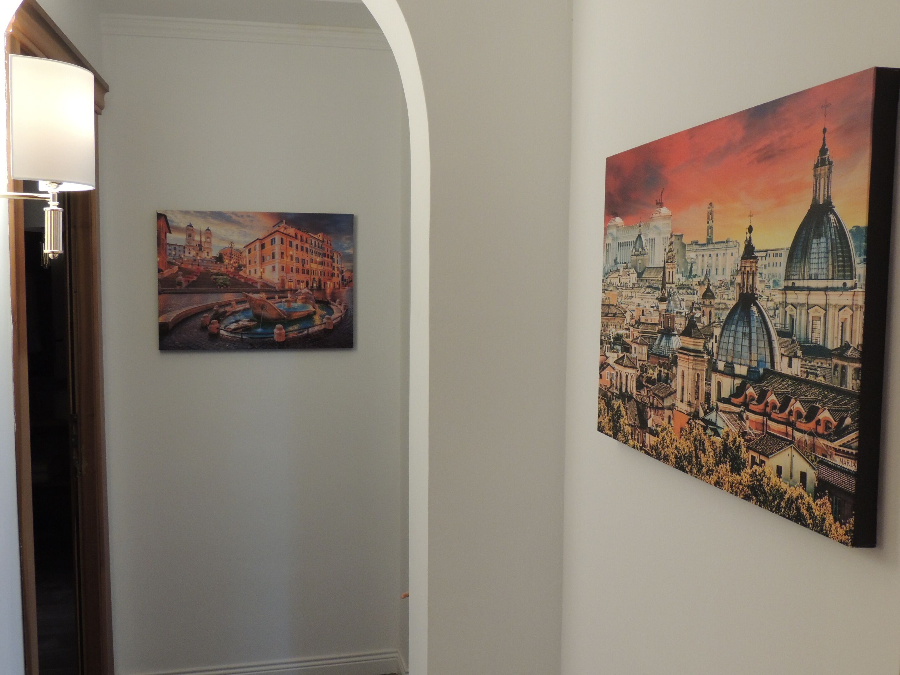 Two paintings of cityscapes on a wall.