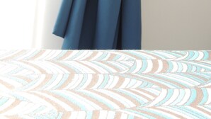 A room with a bed covered in a patterned bedspread, a blue curtain tied at the top, and a plain wall. - Madonna della Neve (Rome)