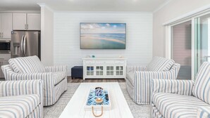 A modern living room with striped sofas, a white coffee table, and a large painting above a white cabinet. - High Tide 3BR Townhome North OC (Ocean City)