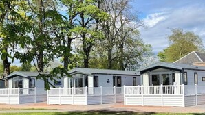A row of white mobile homes with grey roofs, each with a fenced front yard.