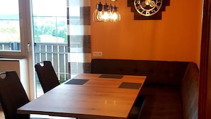 Un coin repas avec une table en bois, des chaises noires et un banc intégré.