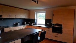 Une cuisine moderne avec des meubles en bois, un plan de travail noir, une fenêtre offrant une belle vue et des appareils électroménagers intégrés.