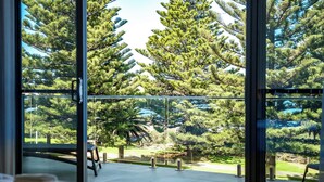 Una habitación con un amplio ventanal que ofrece vistas a un jardín cuidado, con varios árboles y un área pavimentada.