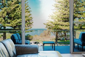 Un balcon avec vue sur la mer, aménagé avec un canapé, des fauteuils et une petite table.