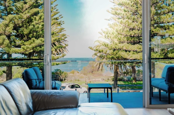Un balcone con vista sul mare, arredato con un divano, sedie e un piccolo tavolino.