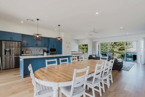 Une cuisine moderne avec des meubles bleus, un réfrigérateur en acier inoxydable et des luminaires suspendus.
