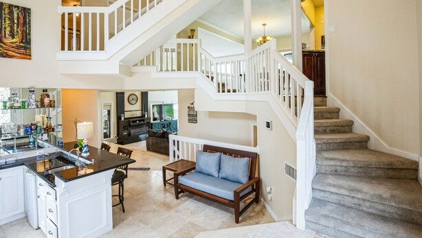A spacious living area with a kitchen, dining area, and a staircase leading to an upper level. - Lakefront Retreat With Private Pool, Hot Tub And Dock 4 Bedroom Home (Montgomery)