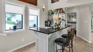 A modern kitchen with a central island, bar stools, and a view of the backyard. - Lakefront Retreat With Private Pool, Hot Tub And Dock 4 Bedroom Home (Montgomery)