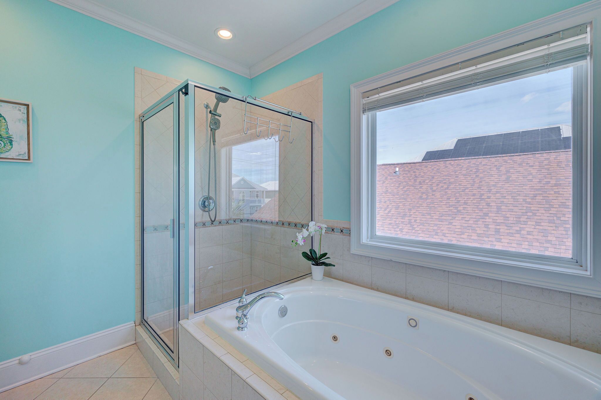 Ein Badezimmer mit einer Duschkabine, einer großzügigen Badewanne und einem Fenster mit Blick auf ein Backsteingebäude.