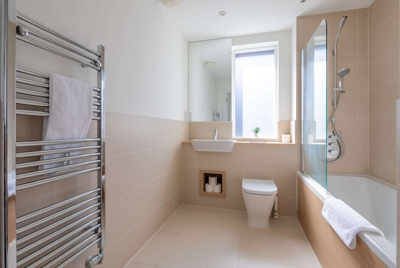 A modern bathroom with a glass shower, a toilet, a sink, and a towel rack.
