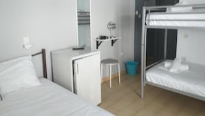 Ein Zimmer mit Etagenbetten, einem Schreibtisch, einem Stuhl, einem kleinen Hocker, einem Spiegel und einer Wanduhr.