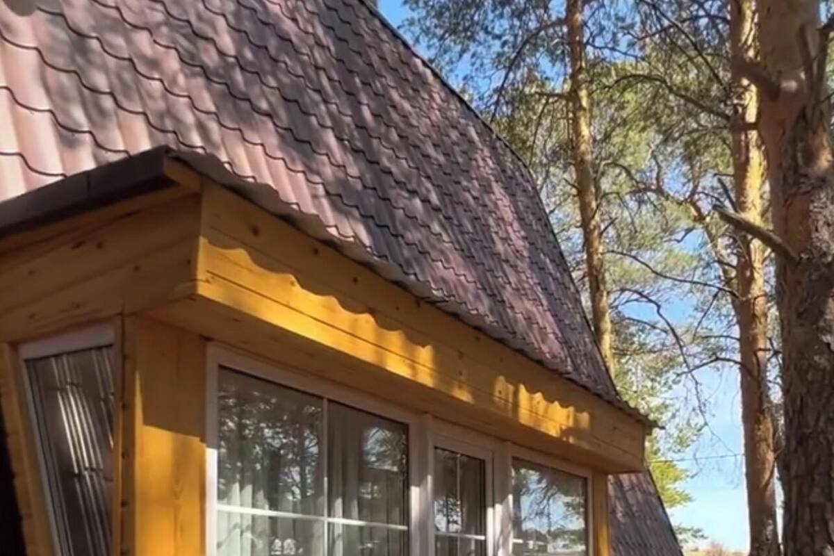 Une cabane en bois avec un toit en pente, de grandes fenêtres et une terrasse en bois.