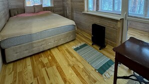 A bedroom with a bed, a radiator, and a window with a view of trees.