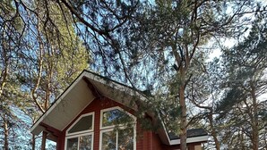 A cabin with a wooden deck, large windows, and a picnic table.