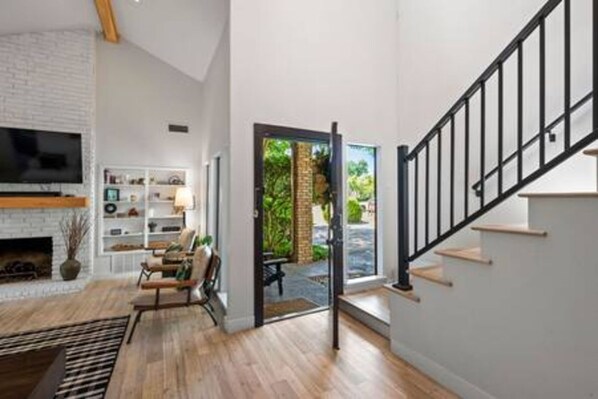 A modern interior with a staircase, a fireplace, and a view of the outdoors.