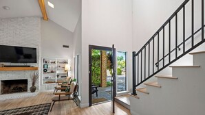 A modern living room with a fireplace, a flat-screen TV, and a wooden floor. - Garland Huge House Unique Treehouse Queen Suite Outdoor Dining Time Together (Garland)