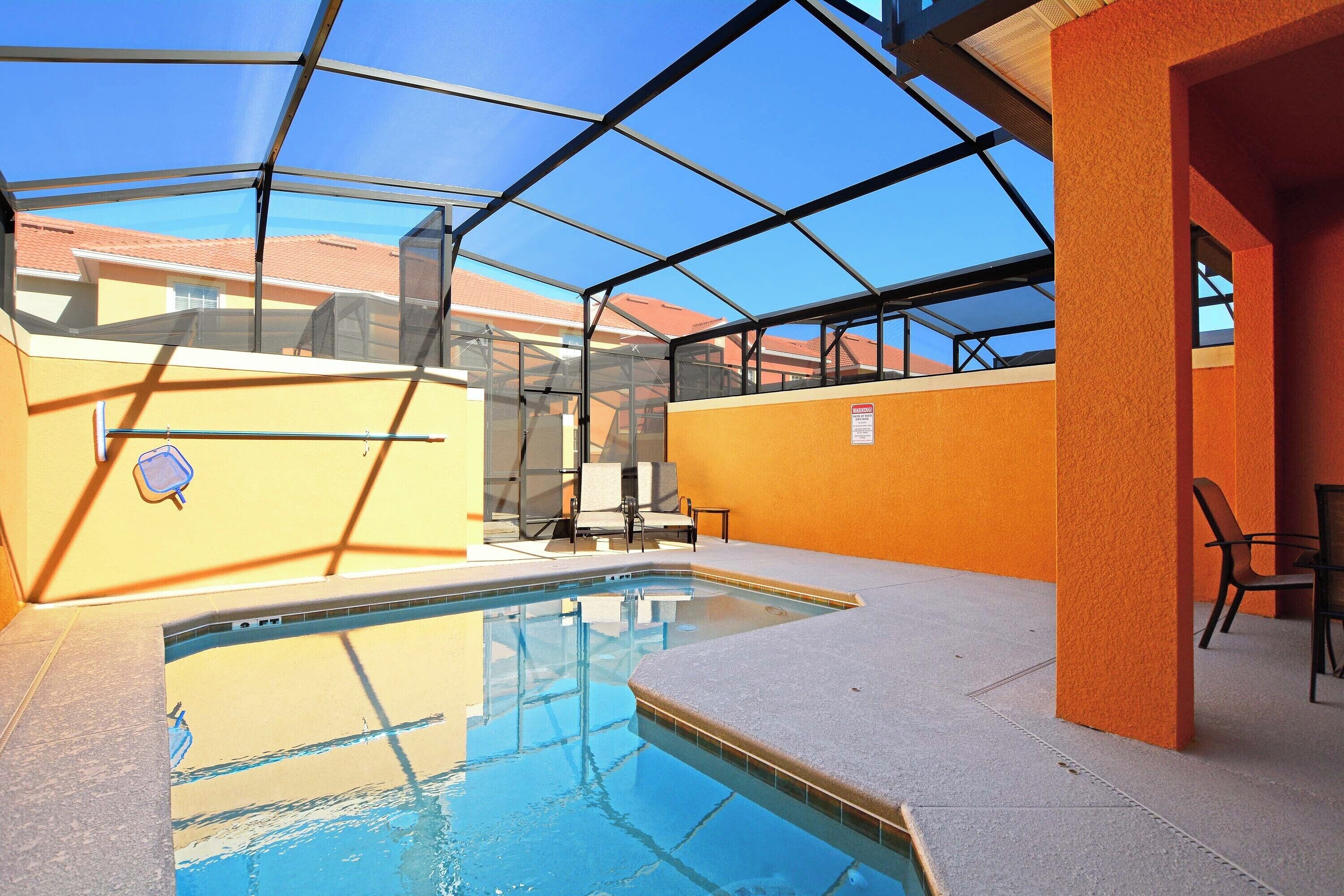 Una piscina interior con techo de vidrio, rodeada de paredes anaranjadas y suelo de baldosas.