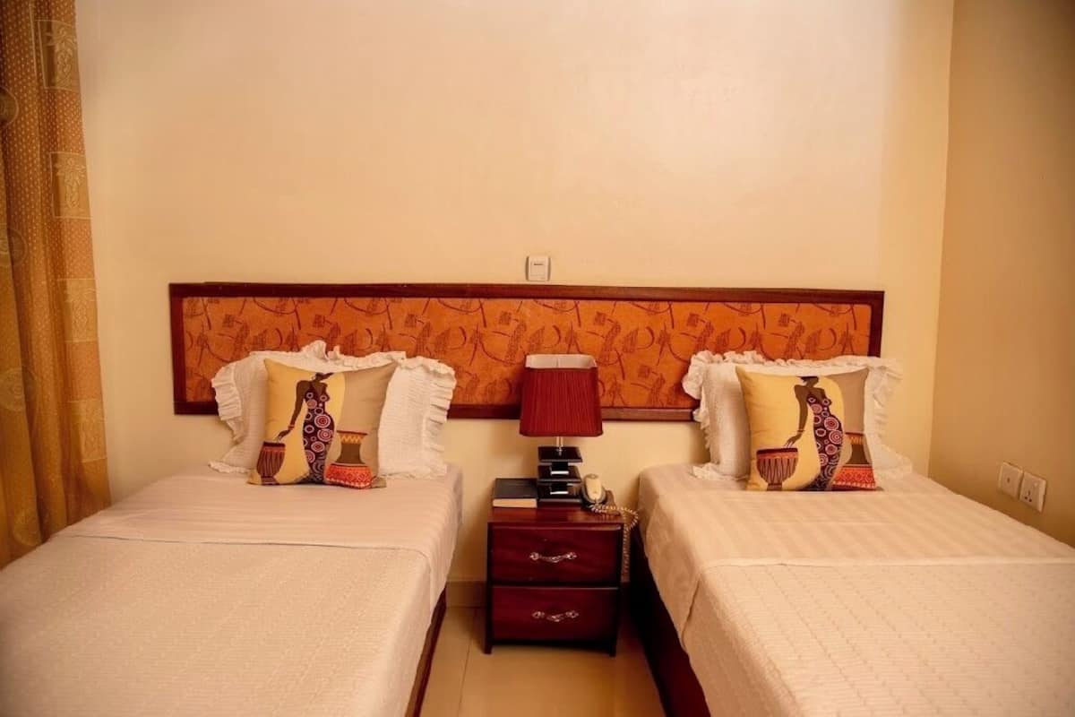 A hotel room with two beds, each with patterned pillows and a wooden headboard.