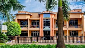 A hotel with a symmetrical facade, multiple balconies, and a central entrance. - HOTEL GREENWICH (Kigali)