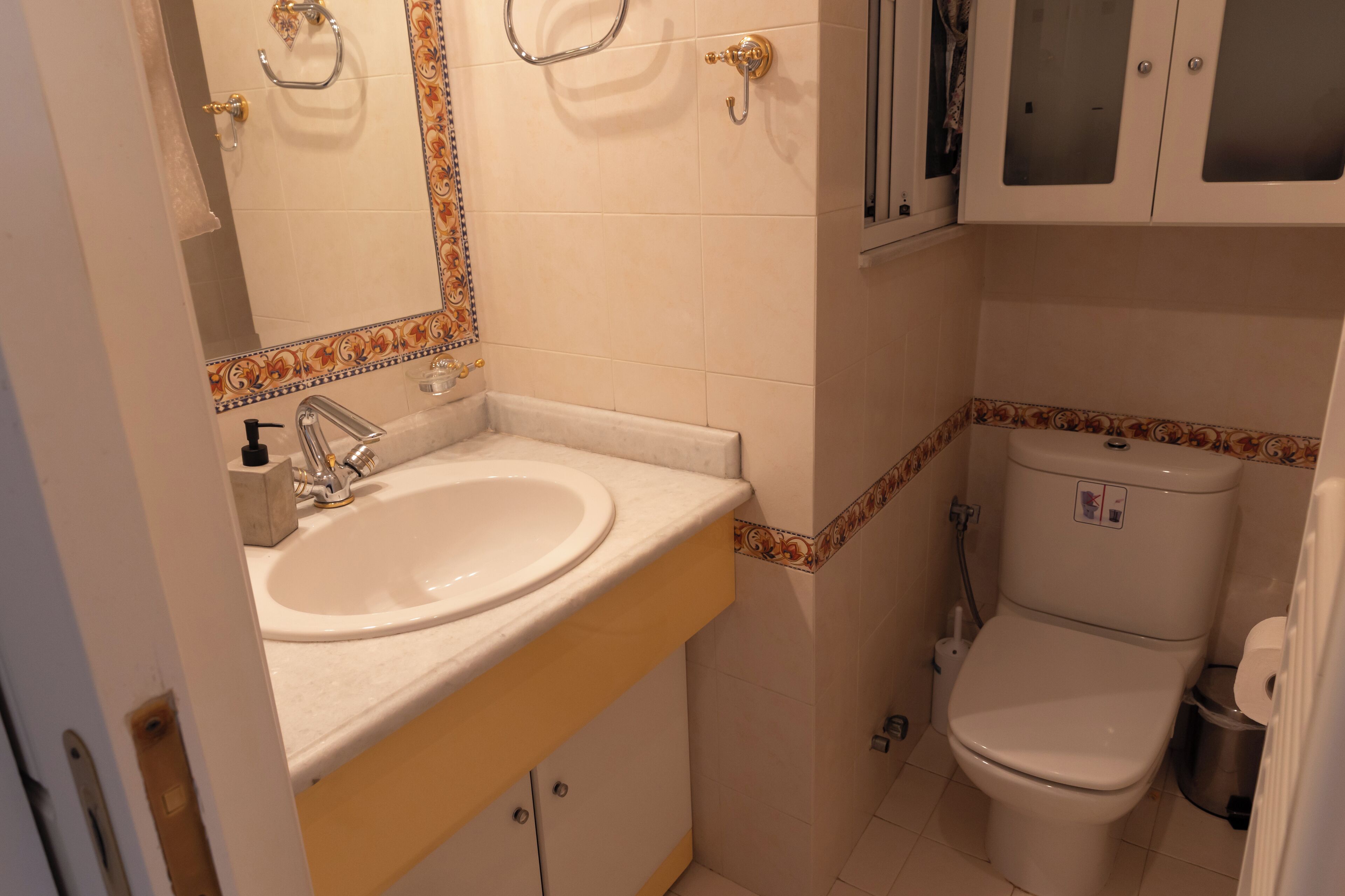 Une salle de bain équipée d’un lavabo, d’un miroir, de toilettes et de placards.