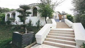 A staircase leading to a white building with arched windows and a tiled roof.