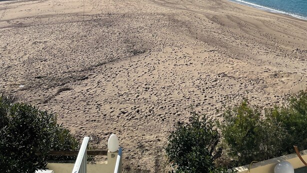 A beach with a clear view of the sea and mountains in the background.