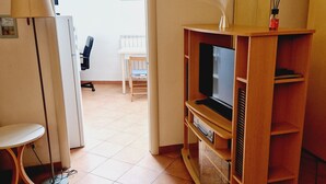 Un salon avec un téléviseur posé sur un meuble en bois, une lampe et une petite table.