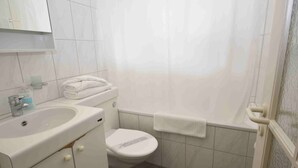 A small, clean bathroom with a sink, toilet, and shower curtain. - Cozy studio in the city center - Crown 34 (Zürich)