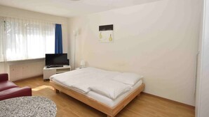 A bedroom with a bed, a TV, a desk, and a chair. - Cozy studio in the city center - Crown 34 (Zürich)