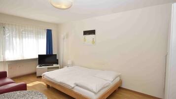 Ein Schlafzimmer mit einem Bett, einem Fernseher, einem Schreibtisch und einem Stuhl.