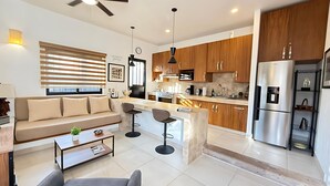 A modern kitchen with wooden cabinets, a stainless steel refrigerator, and a central island with bar stools. - 1 Bed Guesthouse - Bikes - Patio - Gym - Pickleball Court - Golf Cart - Scooters (Chapala)