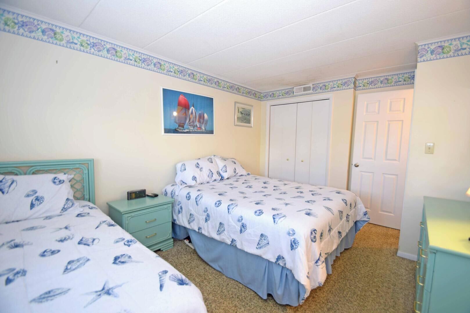 A bedroom with two beds, a wardrobe, and a door.