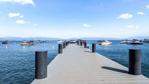 A pier extending into calm waters with boats docked on both sides.