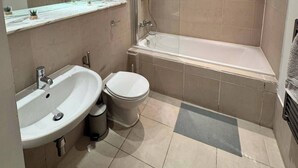 Et moderne badeværelse med badekar, vask og toilet.