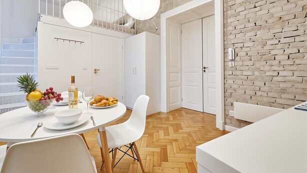 A modern kitchen with white cabinetry, a round dining table, and a brick accent wall. - Cracow Fancy Brick #2 - Old Town (Kraków)