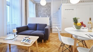 A modern living room with a grey sofa, a wooden coffee table, and a dining area with a white table and chairs. - Cracow Fancy Brick #2 - Old Town (Kraków)