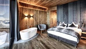 Ein modernes Schlafzimmer mit einem großen Bett, einer Badewanne und einem Sessel.