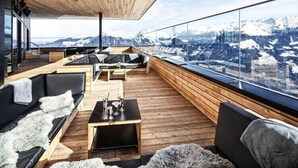 Ein moderner, offener Wohnbereich mit Holzböden und Möbeln, große Fenster mit Blick auf die Berge.