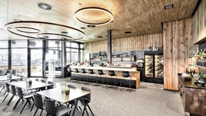 Ein modernes Restaurant mit Holzvertäfelung, großen Fenstern und einer Bar.
