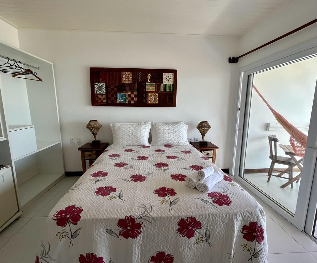 A bedroom with a bed, a wall art piece, a window, and a chair outside.